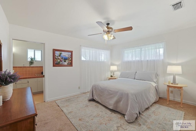 bedroom featuring visible vents, connected bathroom, light carpet, and multiple windows