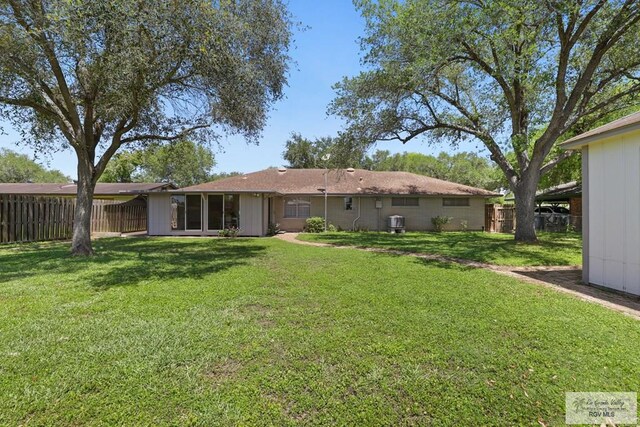 back of house with fence and a lawn
