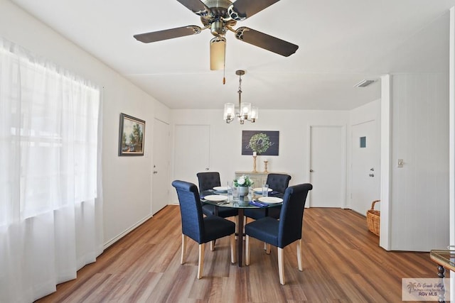 dining room featuring visible vents, wood finished floors, and ceiling fan with notable chandelier