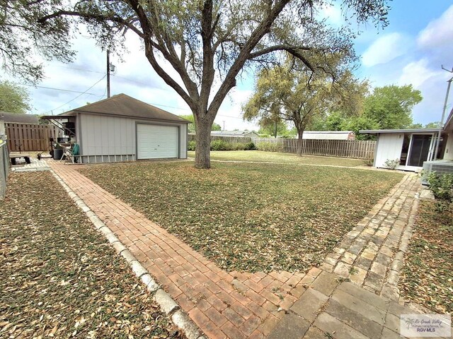 view of yard featuring fence, a detached garage, and an outbuilding
