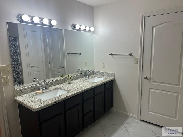 full bath with tile patterned floors, baseboards, a sink, and double vanity