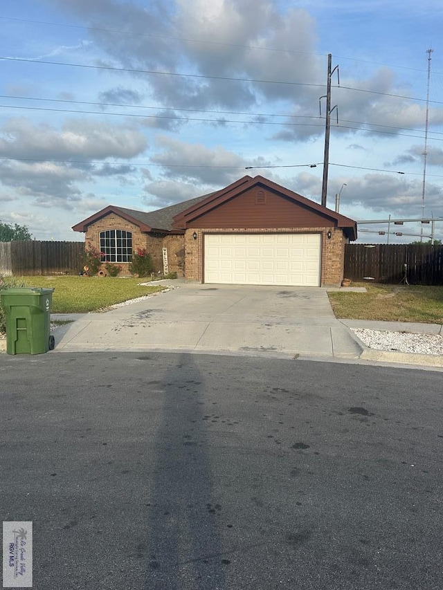 single story home featuring concrete driveway, an attached garage, fence, a front yard, and brick siding