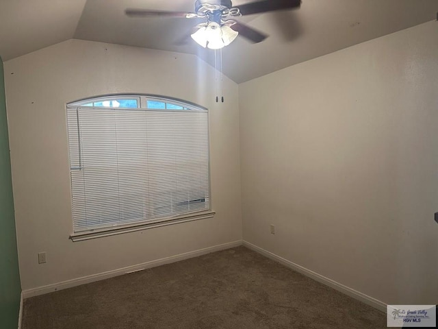 carpeted empty room with vaulted ceiling, a ceiling fan, and baseboards