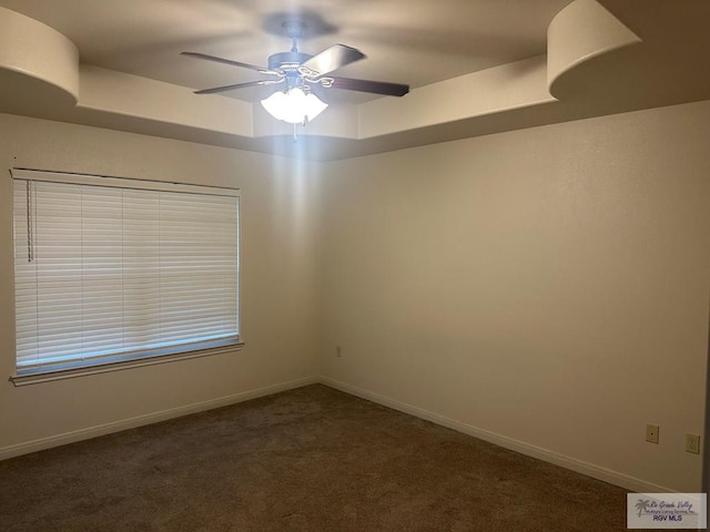 carpeted spare room featuring ceiling fan and baseboards