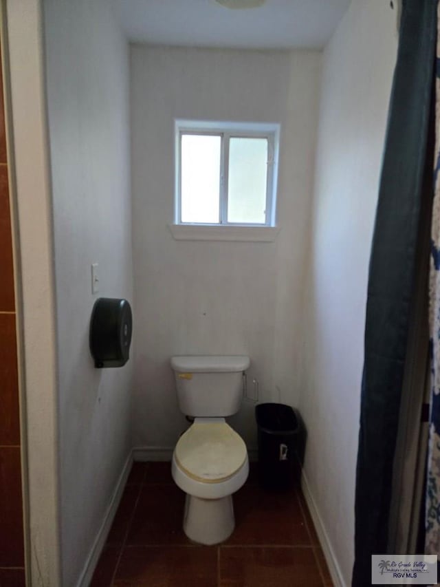 bathroom with baseboards, tile patterned flooring, and toilet