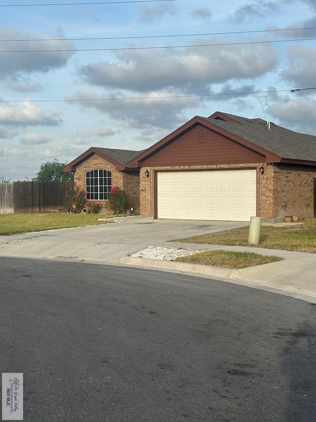ranch-style home featuring brick siding, an attached garage, concrete driveway, and fence
