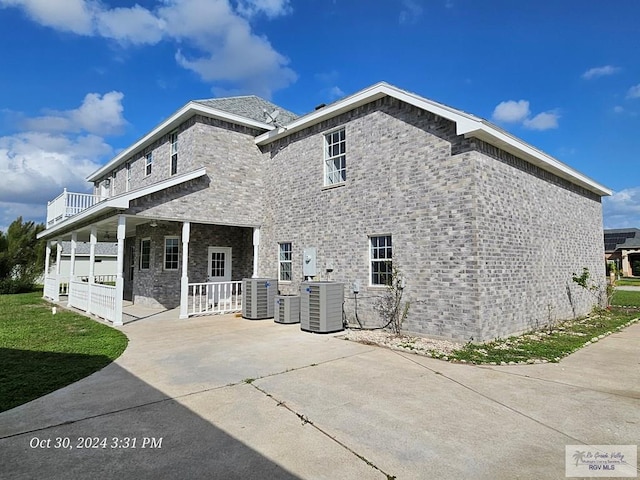 rear view of house with central AC unit, a porch, and stone siding