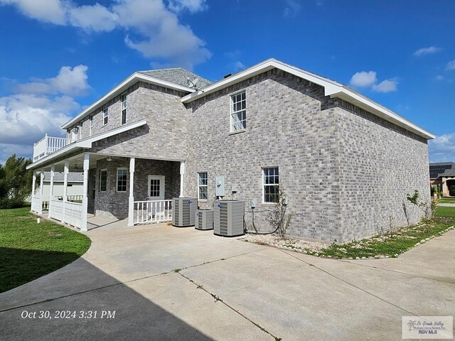 27406 Kelly Ct, La Feria, TX 78559 - rear view of house with central AC unit, a porch, and stone siding