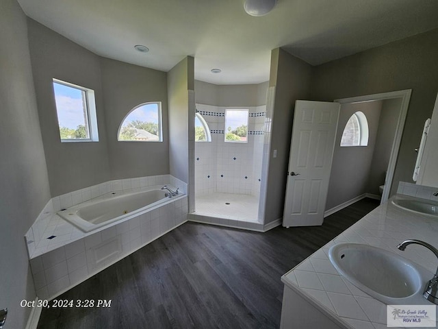 bathroom featuring wood finished floors, plenty of natural light, a shower stall, and a jetted tub