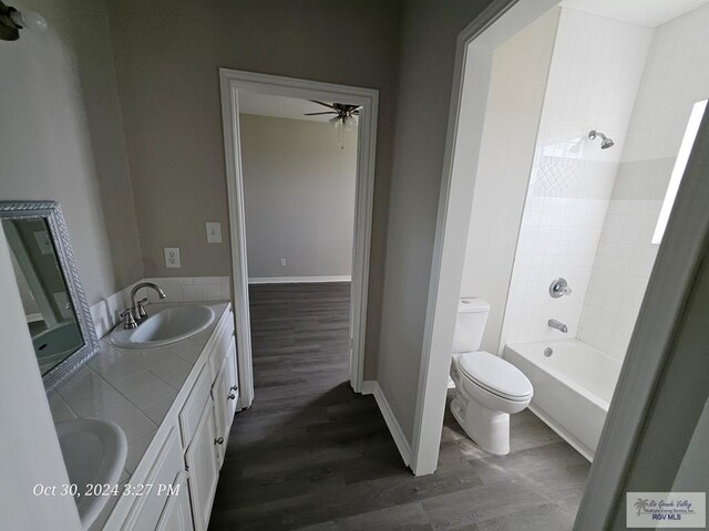 27406 Kelly Ct, La Feria, TX 78559 - bathroom featuring wood finished floors, ceiling fan, toilet, double vanity, and baseboards