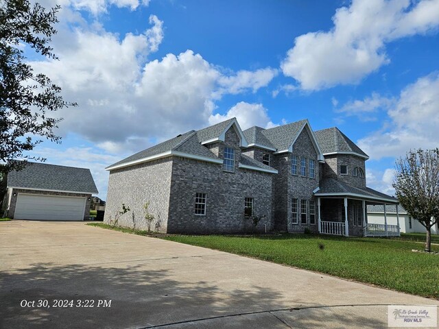 27406 Kelly Ct, La Feria, TX 78559 - view of property exterior featuring an outbuilding, covered porch, a yard, a garage, and brick siding