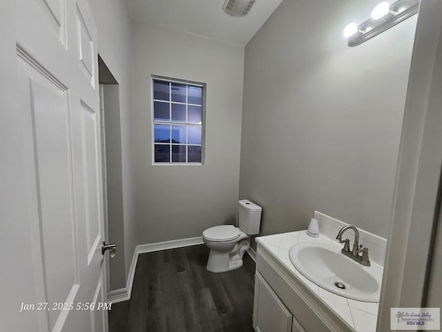 bathroom with wood finished floors, vanity, toilet, and baseboards