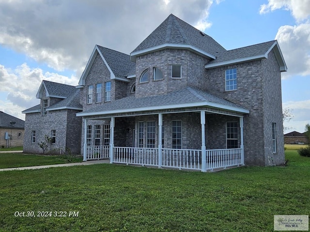 view of front of house featuring roof with shingles, a front yard, and brick siding