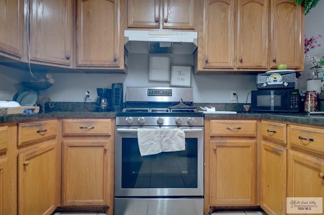 kitchen featuring black microwave, ventilation hood, stainless steel gas range, and dark stone countertops