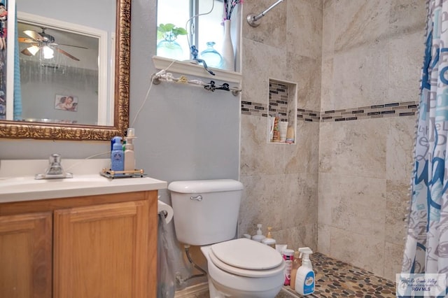 full bathroom with toilet, ceiling fan, tiled shower, and vanity