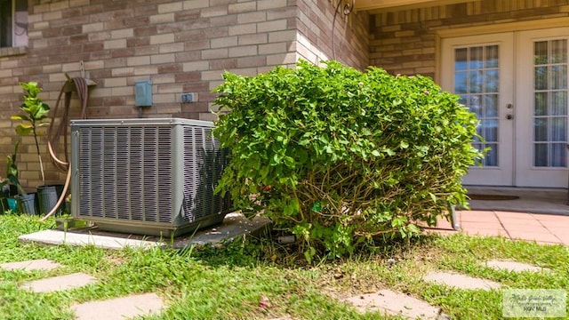 exterior details with brick siding, cooling unit, and french doors