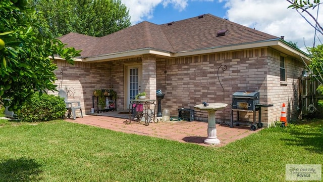 rear view of property featuring a shingled roof, a patio area, a yard, and brick siding