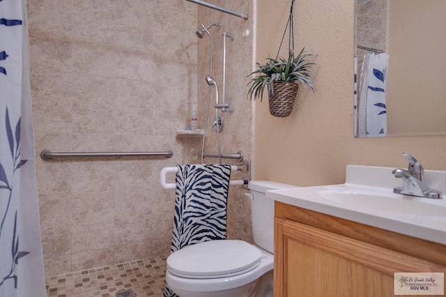 bathroom featuring toilet, tiled shower, and vanity