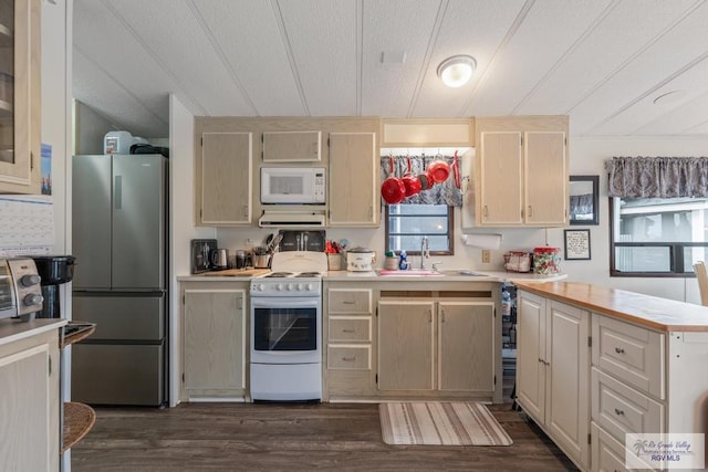 kitchen featuring a peninsula, white appliances, a sink, light countertops, and dark wood-style floors