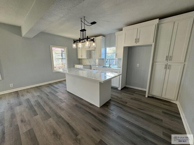 kitchen with pendant lighting, hardwood / wood-style floors, a barn door, a kitchen island, and white cabinetry