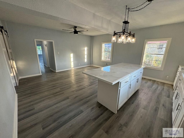 kitchen with a healthy amount of sunlight, a center island, white cabinets, and hanging light fixtures