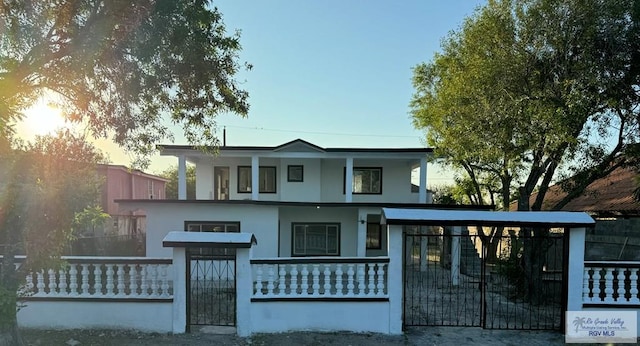 view of front facade with a fenced front yard, a gate, a balcony, and stucco siding