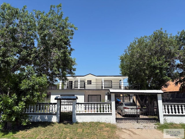 1157 Crockett Ave, Brownsville, TX 78521 - view of front of house with a fenced front yard, a gate, a balcony, and stucco siding