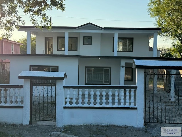 view of front facade with a fenced front yard, a gate, and stucco siding