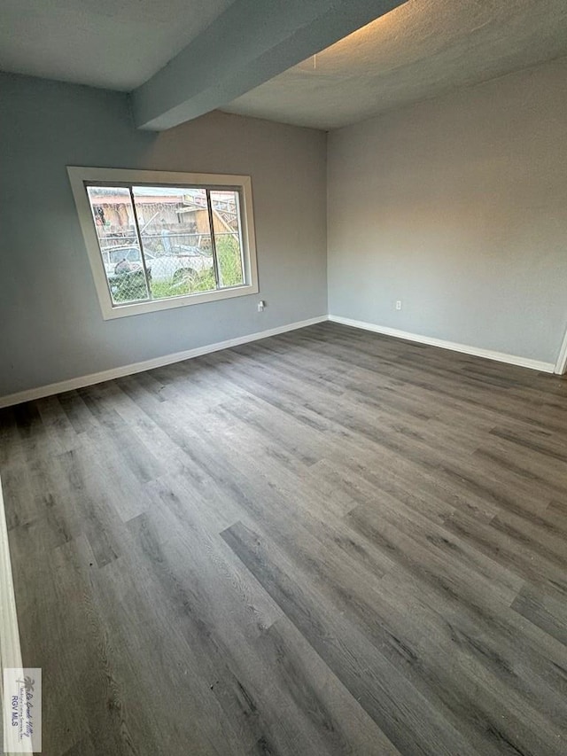 unfurnished room with dark hardwood / wood-style floors, beam ceiling, and a textured ceiling