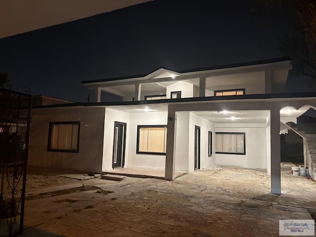 back of house at night featuring a patio area and stucco siding