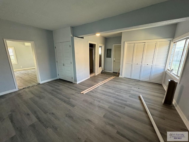 unfurnished bedroom with electric panel, hardwood / wood-style flooring, and ensuite bath