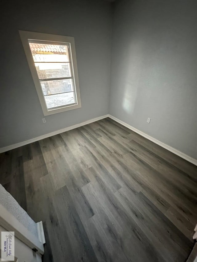 empty room featuring dark wood finished floors and baseboards