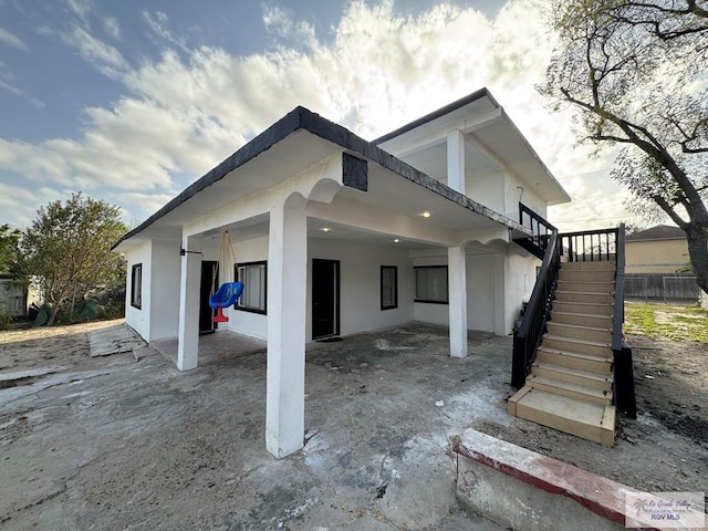 view of side of home with stairs and a patio