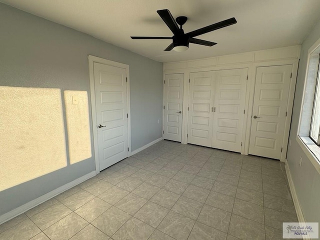 unfurnished bedroom featuring a closet, ceiling fan, baseboards, and light tile patterned floors