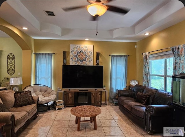 living room featuring ceiling fan, light tile patterned flooring, and a raised ceiling