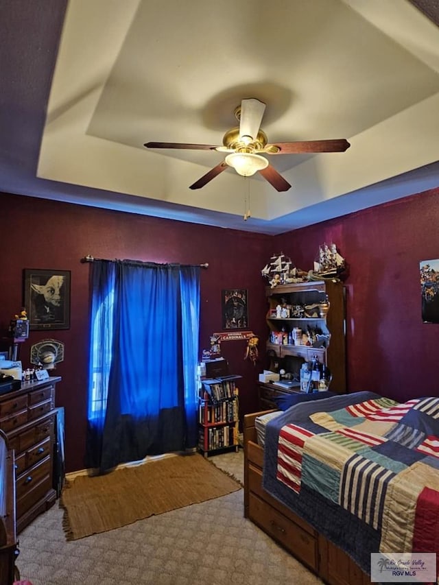 carpeted bedroom featuring a raised ceiling and ceiling fan