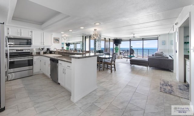 3000 Gulf Blvd, South Padre Island, TX 78597 - kitchen with stainless steel appliances, open floor plan, a peninsula, light marble finish floors, and white cabinets