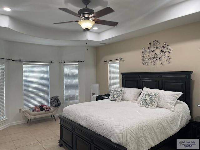 tiled bedroom featuring multiple windows, a raised ceiling, and ceiling fan