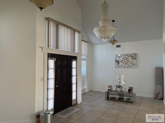 entrance foyer with a notable chandelier, light tile patterned flooring, and vaulted ceiling