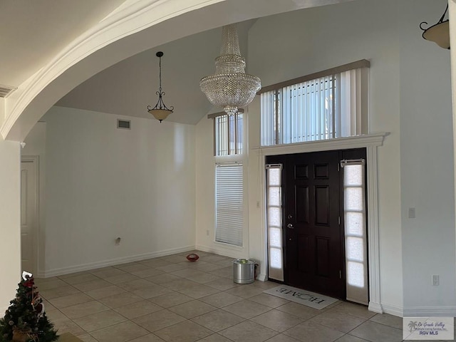 foyer entrance with light tile patterned floors, a towering ceiling, and a chandelier