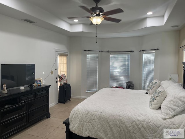 tiled bedroom with a raised ceiling and ceiling fan