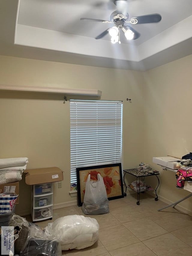 sitting room with light tile patterned floors, a tray ceiling, and ceiling fan