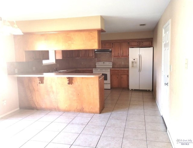 kitchen with white appliances, a kitchen breakfast bar, tasteful backsplash, and kitchen peninsula