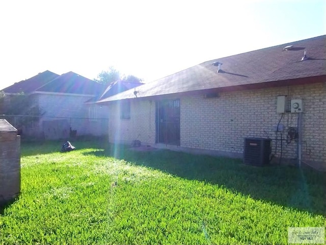 rear view of house featuring a yard and central AC unit