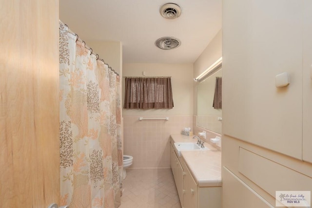 bathroom with vanity, tile walls, and toilet