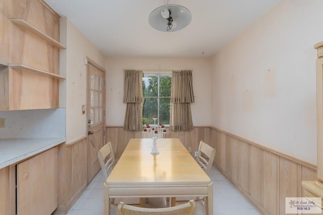 dining space featuring ceiling fan and wood walls