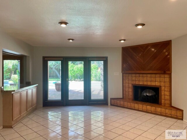 unfurnished living room with a tile fireplace, light tile patterned floors, and a textured ceiling