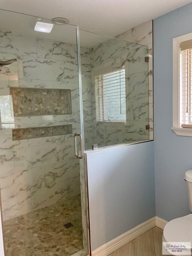 bathroom featuring hardwood / wood-style floors, a shower with door, and toilet