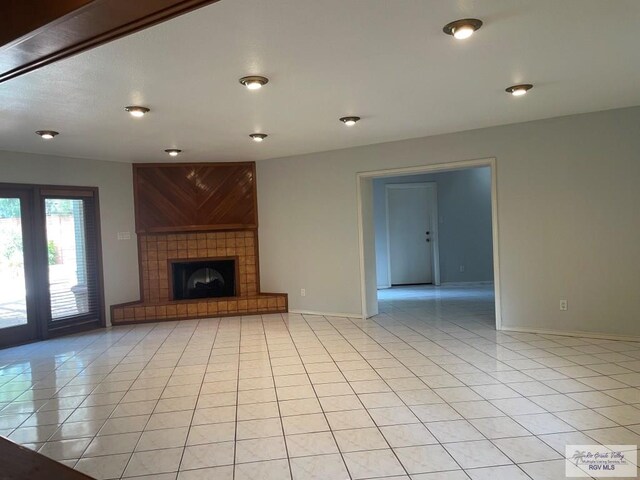 unfurnished living room featuring a tile fireplace and light tile patterned flooring