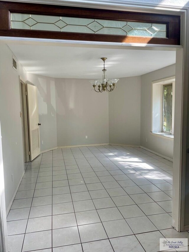 tiled empty room with a notable chandelier